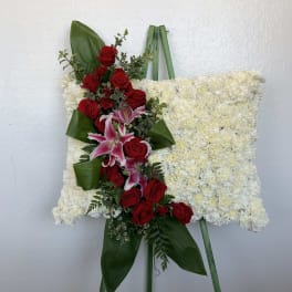 Standing floral spray with red roses and pink lilies on a white flowered easel
