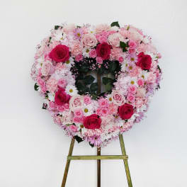 Heart-shaped floral wreath on an easel with pink and white roses