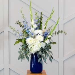 White and blue floral arrangement in a cobalt vase
