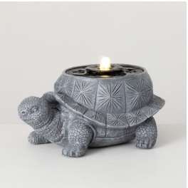 Gray turtle-shaped candle holder with a lit candle on top