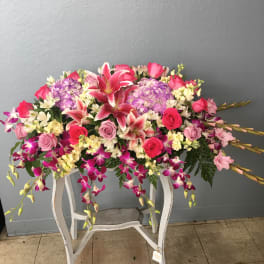 Large pink and purple floral arrangement on a white stand