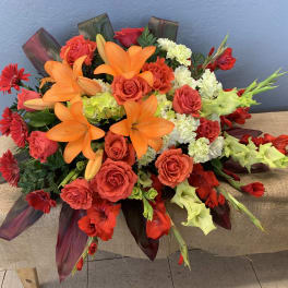 Bright bouquet of orange lilies, red roses, and red gerbera daisies