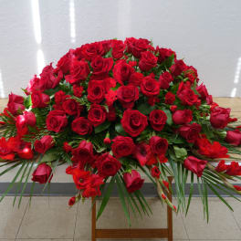Large red rose arrangement with palm fronds on a table