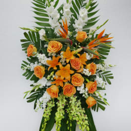 Tall standing floral spray with orange roses, white blooms, and tropical leaves