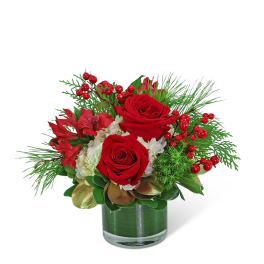 Red roses and red flowers in a glass vase with berries