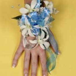 White flower corsage with blue ribbon on a hand
