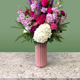 Pink and white floral arrangement in a tall pink vase