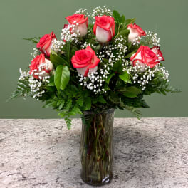 Vase arrangement of red and white roses with baby's breath in a clear glass vase on a stone countertop