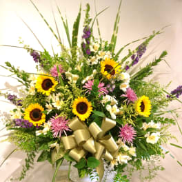 Large mixed bouquet with sunflowers, pink blooms, and a gold ribbon