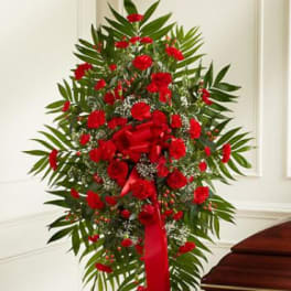 Tall standing spray of red flowers with a red ribbon