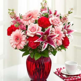 Pink and red mixed bouquet in a red glass vase