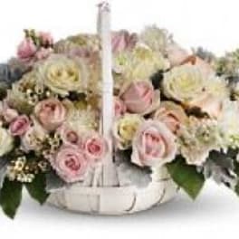 Pink and cream rose arrangement in a white basket with a handle