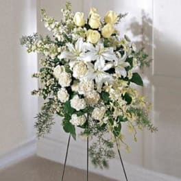 Standing floral spray with white lilies, pale yellow roses, and white filler flowers