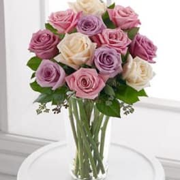 Bouquet of pink, lavender, and white roses in a clear glass vase