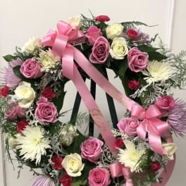 Pink and white rose wreath with ribbon on a stand