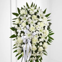 White floral standing spray with ribbon on an easel