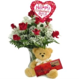 Red roses in a vase with a teddy bear and Valentine heart balloon