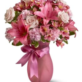 Pink and white mixed flower bouquet in a pink vase with ribbon