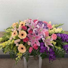 Large casket spray with pink lilies, gerbera daisies, and purple flowers