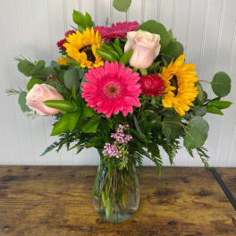 Mixed bouquet of pink, yellow, and pale roses in a glass vase