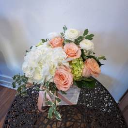 Low arrangement of white hydrangeas, peach roses, and white blooms in a rustic wooden box.