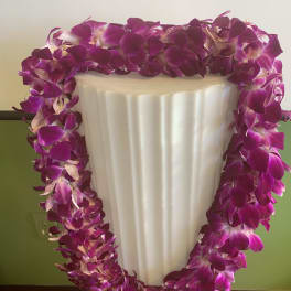 Purple orchid lei draped over a white pedestal vase