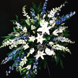 White lilies and blue delphinium in a large spray arrangement