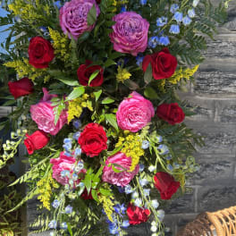 Standing floral spray with red and pink roses and blue flowers