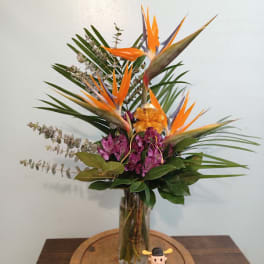 Tropical flower arrangement with orange bird-of-paradise in a glass vase