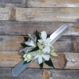 White orchid corsage with silver ribbon on a wooden surface