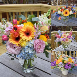 Colorful mixed bouquet in a clear glass vase on a wooden table