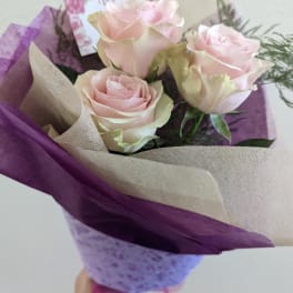 Bouquet of pale pink roses wrapped in purple and beige paper