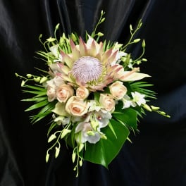 Bouquet with pale roses, white orchids, and a large protea center