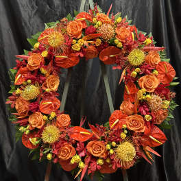 Circular floral wreath with orange and red flowers on a stand