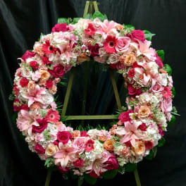 Large floral wreath with pink and white flowers on a stand