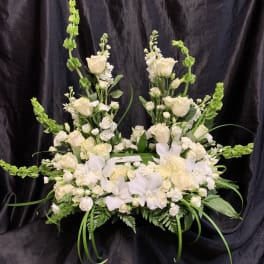 Large white floral arrangement with roses and orchids on a black backdrop