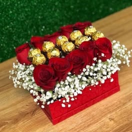 Red roses and gold-wrapped chocolates in a red box with white baby's breath