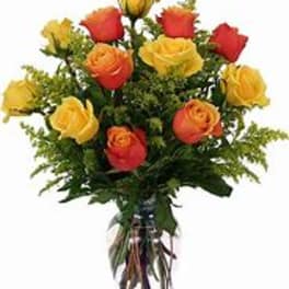 Yellow and orange roses arranged in a clear glass vase with filler accents