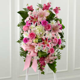 Standing pink and white floral spray with lilies and roses on a white easel