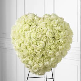 Heart-shaped arrangement of white roses mounted on a black metal easel