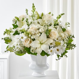 White lilies and roses arranged in a white vase
