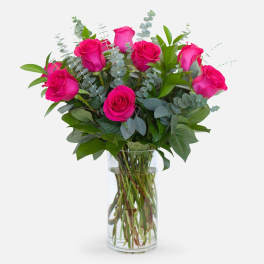 Pink roses in a clear glass vase with eucalyptus greenery