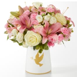Pink lilies and cream roses arranged in a white vase with a gold dove design.