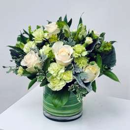 White roses and pale green flowers in a green glass vase