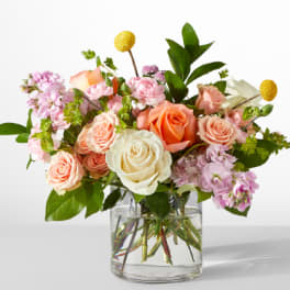 Bouquet of peach, white, and pink roses in a clear glass vase