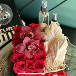 Red roses and pink orchids arranged with candles in a white gift box