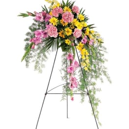 Standing floral spray with pink and yellow flowers on a black easel