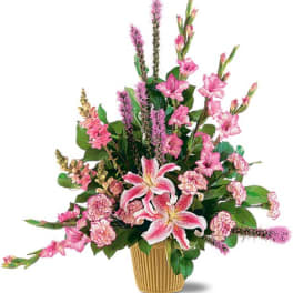 Pink lilies and mixed pink flowers in a ribbed gold vase