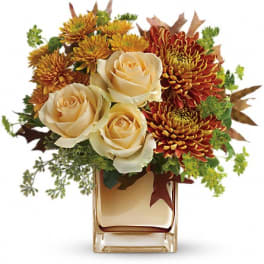 Bouquet of cream roses and orange chrysanthemums in a square glass vase