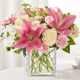 Pink lilies, cream roses, and carnations in a clear glass vase